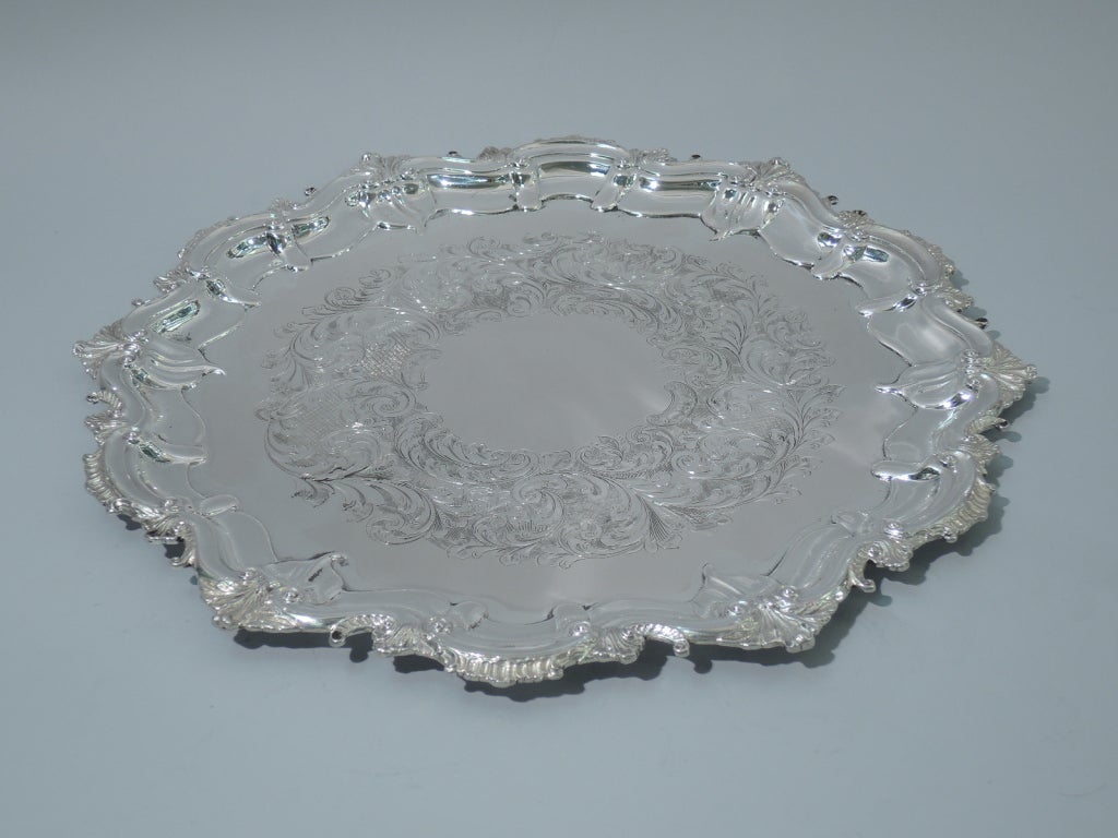 Georgian-style sterling silver serving tray. Made by Roden Bros. Ltd in Toronto, ca. 1950. Circular with stippled foliage applied to scrolled rim. Wreath of scrolls and foliage engraved in center. Hallmarked by Roden Bros., a Canadian silver maker