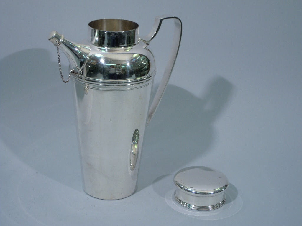 Large sterling silver martini shaker. Made by Tiffany in New York, ca. 1950. Tapering bowl, scrolled-bracket handle, diagonal spout with chained cap, and short neck with bun cover. Party size. A fine postwar version of a pattern (no. 21357) that was