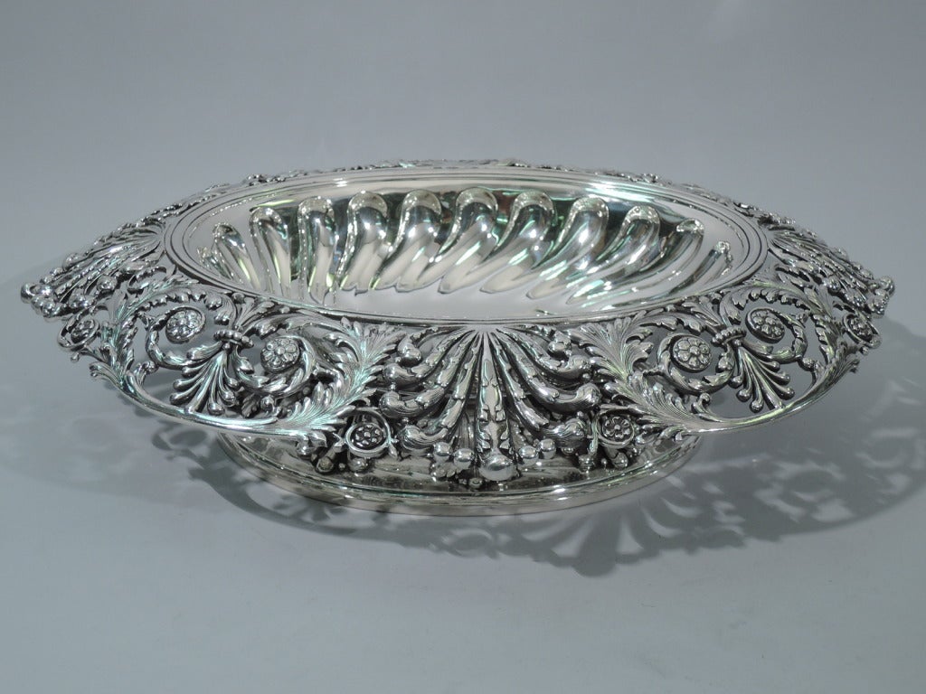 Large and heavy sterling silver centerpiece bowl made by Tiffany & Co. in New York c1905. Solid oval well with twisted gadrooning in repousse. Wide and rolled rim with open scrolls, flowers and foliage. The pattern (no. 16531) was first produced in