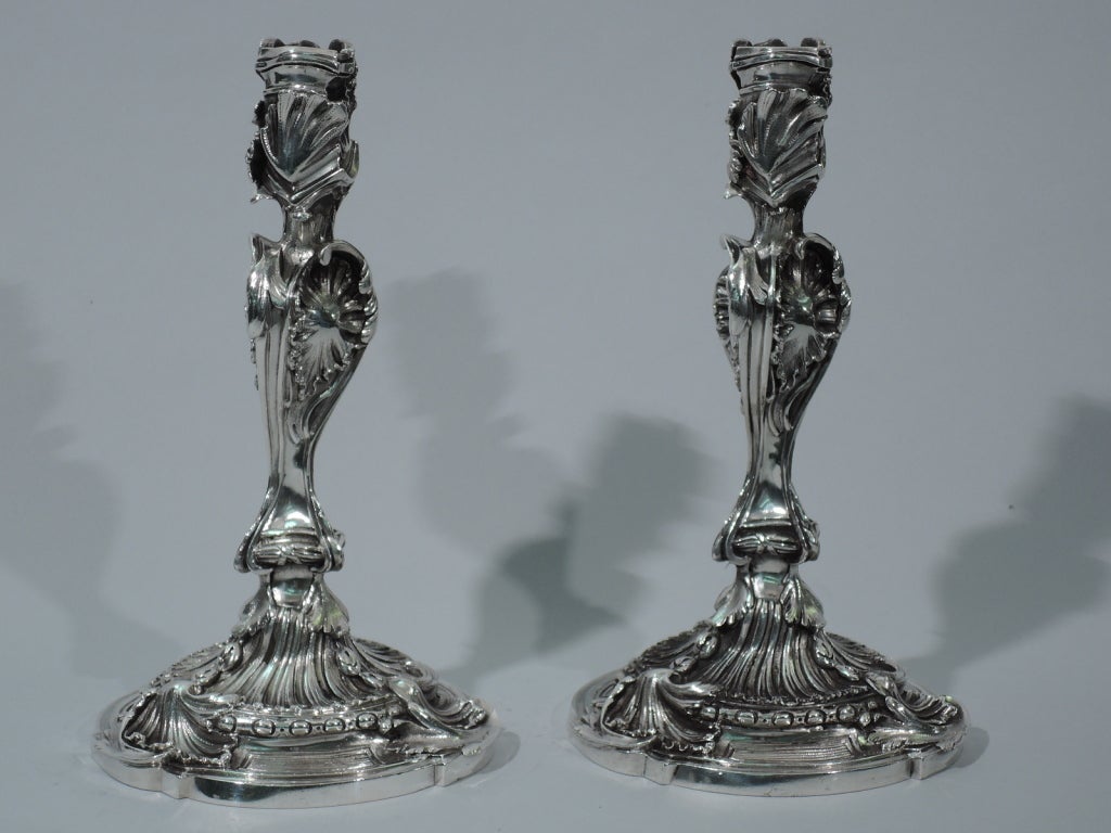 click to view larger picturesPair of 950 silver candlesticks. Made by Cardeilhac in Paris, ca. 1910. Each: twisted baluster stem on double-dome foot. Raised and applied shells, foliage, and scrolls. Socket is asymmetrical with overlapping foliage.