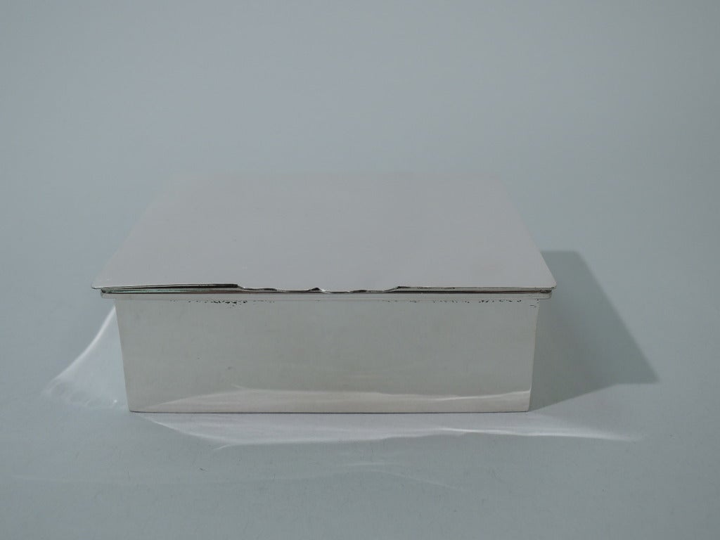 Sterling silver box. Made by Andrew Taylor in Newark, ca. 1940, for Cartier. Rectangular with crisp corners and molded rim. Cover is flat and hinged with scalloped tab. Box interior cedar lined. Hallmarked by Andrew Taylor and Cartier. Excellent