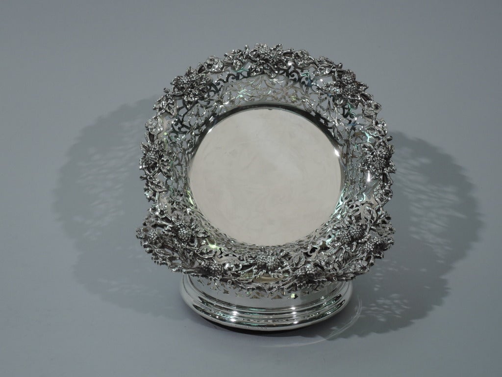 Pair of sterling silver wine bottle coasters. Made by Dominick & Haff in New York, ca. 1890, for Bailey, Banks & Biddle in Philadelphia. Each: open scrollwork and flared rim with applied berries. Molded base mounted to felt-lined wood. Hallmark