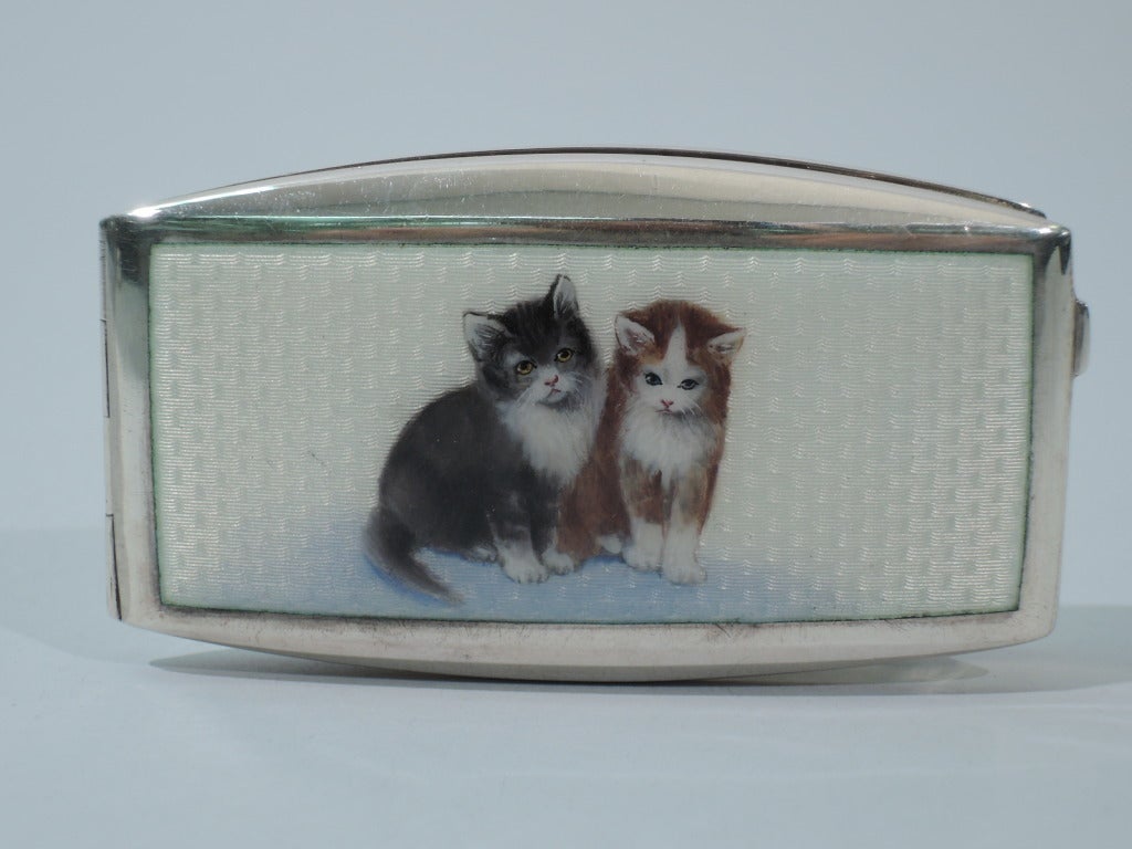 Cigarette case in 900 silver with enamel cats. Made by FB in Austria, ca. 1920. Rectangular with curved sides and hinged cover. On cover are a couple kitties sitting pretty. They have stiffened forelegs and downcast eyes. They look remorseful – but