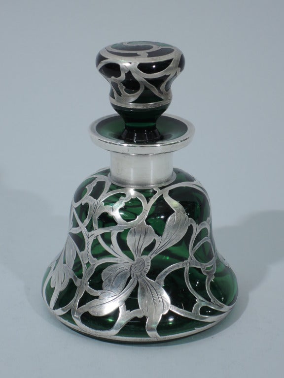 Emerald glass perfume bottle and stopper with 999 silver overlay. Bottle: bell form with short neck and everted rim. Stopper: inverted bell with short and tapering plug. Asymmetrical floral overlay with daisies. Some petals are missing, in the