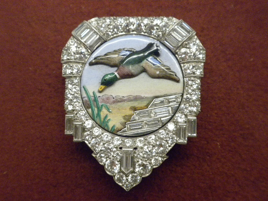 Fabulous Art Deco Platinum, Enamel, and Diamond Clip, probably by William Scheer for Raymond Yard, circa 1930. The clip is designed as an enamel plaque with a flying duck, framed by platinum set bead and channel-set diamond baguettes totaling