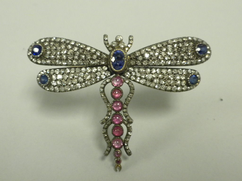 This Diamond, Sapphire and Ruby Silver topped Gold Mounted Dragonfly Pin is a specimen example of the art of the 19th Century French Goldsmith.  The Dragonfly is beautifully and expertly made in realistic form, with collet set sapphires and rubies,