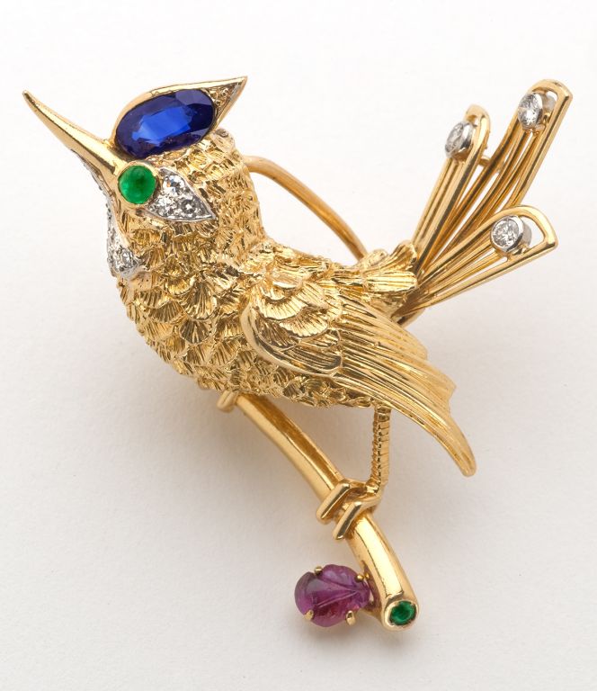 This elegant and personable Bird Pin features diamonds, a carved ruby leaf, emerald eye and sapphire head, 18 karat yellow gold, with French maker's mark.