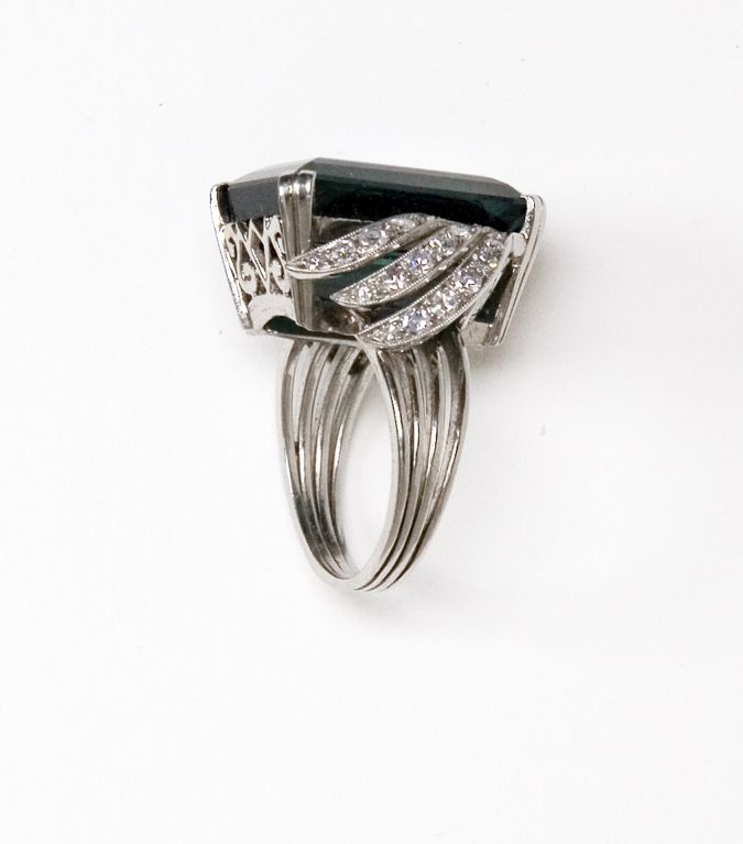 Emerald Cut Teal Green Tourmaline Ring with Diamond Accents in the syle of H. Stern.  The mounting is platinum and features a gorgeous 21.78 carat tourmaline measuring 19.46 x 13.55 x 9.44 mm VVS clarity and 34 single cut diamonds totaling
