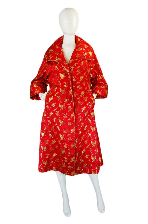 This is perhaps one of the most beautiful vintage coats I have ever had in the shop. It is made from a stunning, jaw dropping Asian red silk, very luxurious quality silk inside and out. Woven through the exterior is  gold threading depicting pots,