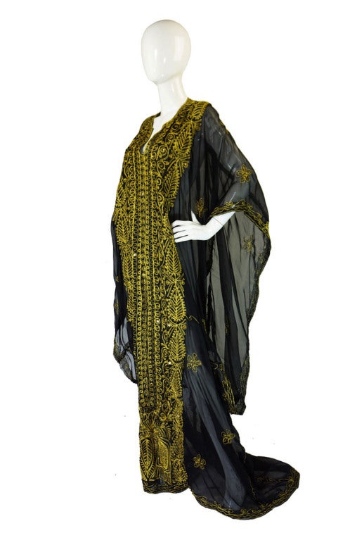 A gorgeous late 1970s caftan done in a feather light, textured silk-cotton mix, almost chiffon-like fabric, that has gold metallic designs embroidered onto it. The caftan is cut supermodel long and is almost weightless - really floaty and light in