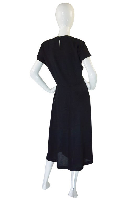 What a glorious 1940s swing dress! Made out of a black silk crepe that drapes wonderfully when on. It has that touch of thirties influence still with a slightly wider cut through the bodice and looser drape which makes it very flattering. The skirt