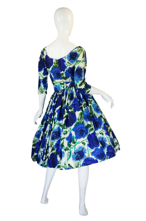 This Suzy Perette dress is a beauty! It is made of soft cotton that has a stunning combination of deep blues flowers with pops of greens screened onto it. The bodice is kept simple and fitted to the body with a wide shoulder for a hint of