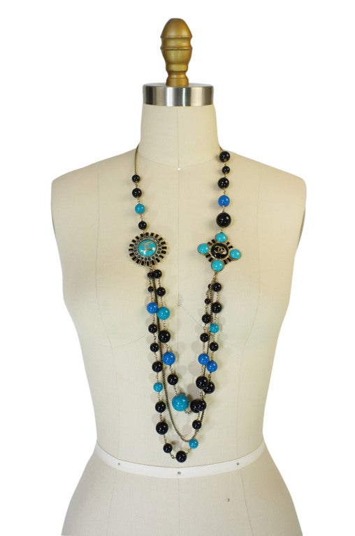 Beautiful Chanel 07A collection necklace. Comprised of opaque glass pearl beads in black and two tones of blue. Large signature Chanel logo embossed medallions set on either side. This is an outstanding piece that was produced in limited quantities