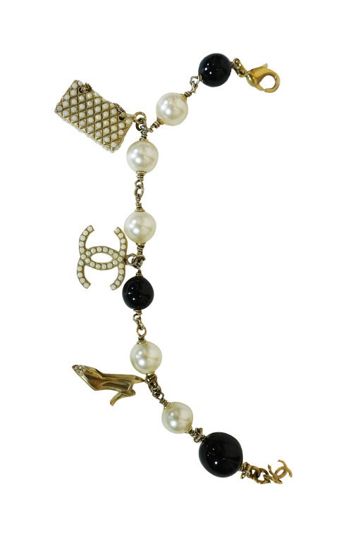 Beautiful Chanel charm bracelet. Comprised of opaque glass pearl beads in black and white. Three charms - a gold, heeled shoe with tiny rhinestone studded toe, the iconic double Cs detailed with fine little faux pearls black on one side and white on