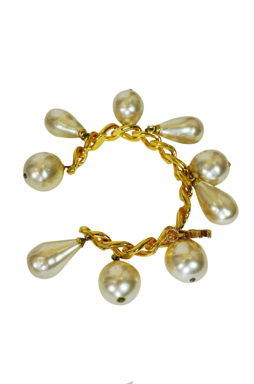 Amazing 1986 Chanel pearl bracelet cuff. Huge drop glass pearls are set in a rigid and shaped gold chain base that just slips on the wrist. A small double C charm is set on one side. This is an outstanding piece that was produced in limited
