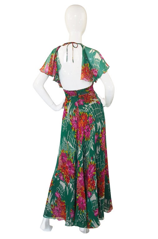 A stunning and very sexy, bias cut silk chiffon dress by the great American designer Scott Barrie. The almost weightless silk is printed with a beautiful and tropical feeling design that has huge pink and coral flowers on a vivid green backdrop. It