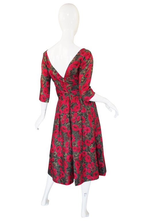 Made of a stunning combination of red on pink and deep hued greens on silk, this Suzy Perette dress is a beauty! The front is is simple with a curved and plunged neckline that is mirrored in the back except the back plunge goes quite deep. The waist