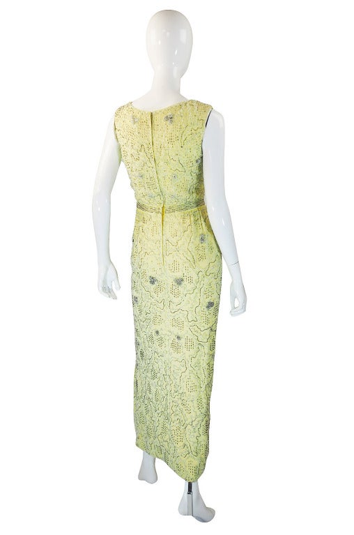 This dress in person is the perfect pale, cool yellow and is so flattering on most skin tones! Made of a silk crepe that is completely hand beaded with clear and silver toned beads that trail over the dress with denser clusters of beads worked