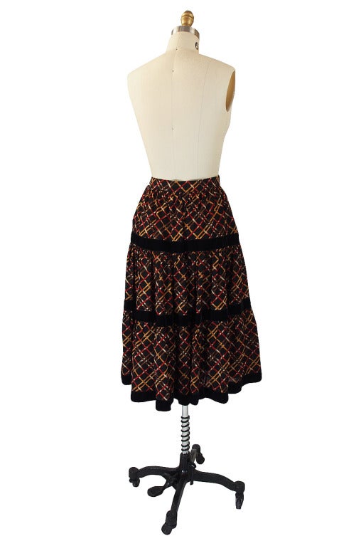 The plaid pattern is screened onto a fine wool challis base on this fabulous YSL skirt. Made into three tiers of fabric with each tier getting fuller as it nears the hem. Separating the tiers are bands of black velvet and on the very top at the