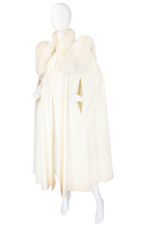 Dramatic only begins to cover how to describe this killer winter white cape! It is cut with strong powerful lines that are further emphasized by that over the top fur detailing that gives the shoulders a high couture, runway feel.The cape itself is
