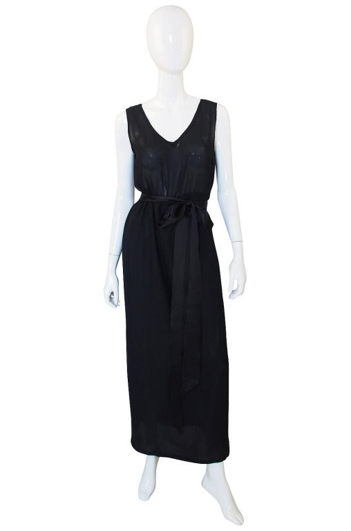 An incredible set, this Givenchy ensemble is comprised of a black silk chiffon inner dress over which a lace overlay sits and then is belted at the waist with a silk satin sash. The inner dress is a simple, sleeveless sheath with elastic at the
