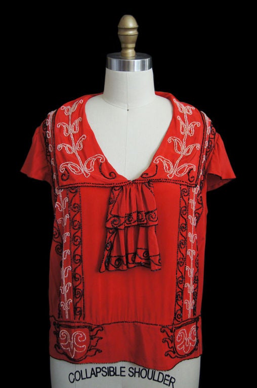 Gorgeous red silk flapper blouse with beautiful hand bead work in a wonderful example of the care taken in even the separates in the twenties! This is an exceptional example of what was probably a day  piece and a modern girl could work it into her