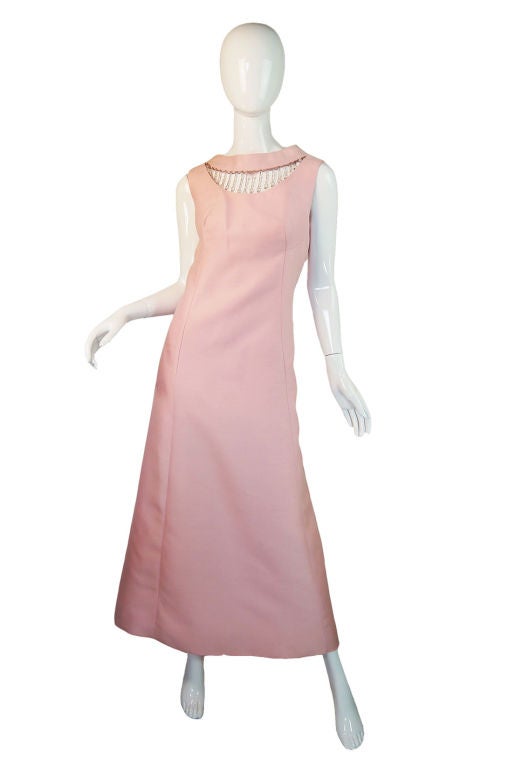 Simple and chic this mid-sixties silk blend pink gown is the very definition of hostess glamour from the time period. Cut on an A-line the skirt swoops out to a wide A-line from the undefined waistline. The shape is created by vertical seaming so