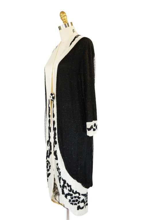 Silk and netting have been hand beaded on this delicious 1920s Cocoon evening coat. Unlabeled but so exceedingly well done that it could perhaps be one pf the greats of that time period. The base is black silk netting on a black tissue silk lining