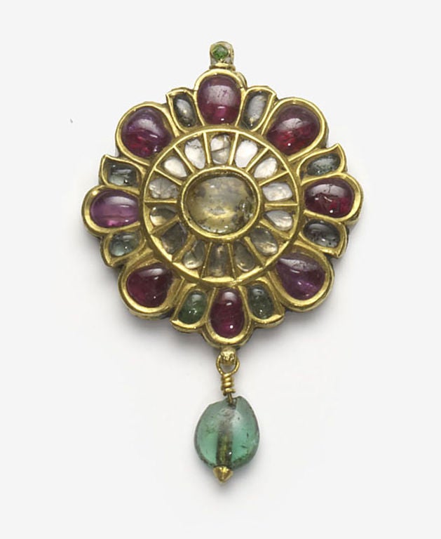 An elegant gold pendant in the form of a flower inset in the kundan style with eight cabochon rubies, interspersed with emerald cabochon in the form of small leaves.The second ring has twelve small diamonds surrounding the central stone which is