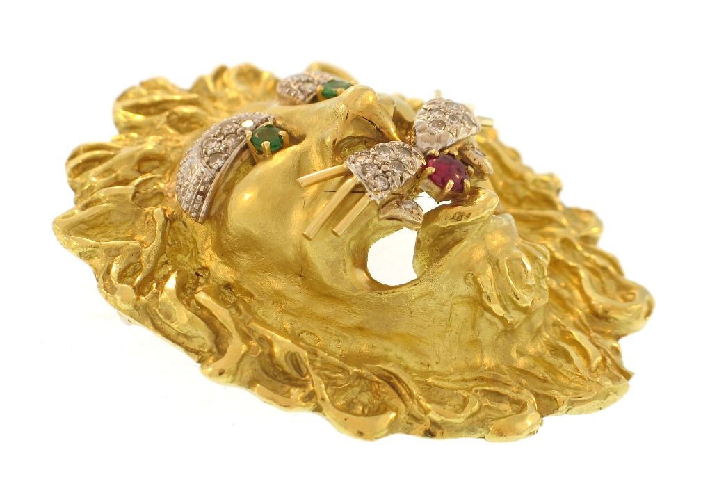 This heavy bold and classic lion head design has a deeply textured mane, diamond eyebrows and whiskers, emerald eyes, and a ruby tongue. Marked HB for Hammerman Brothers. It can also be worn as a pendant or clip over pearls.