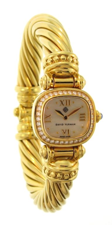 This classic twisted bangle design watch from DAVID YURMAN features a heavy 18k yellow gold bracelet, a cushion shaped case, diamonds, and a mother of pearl dial. This best fits a 6-6/2