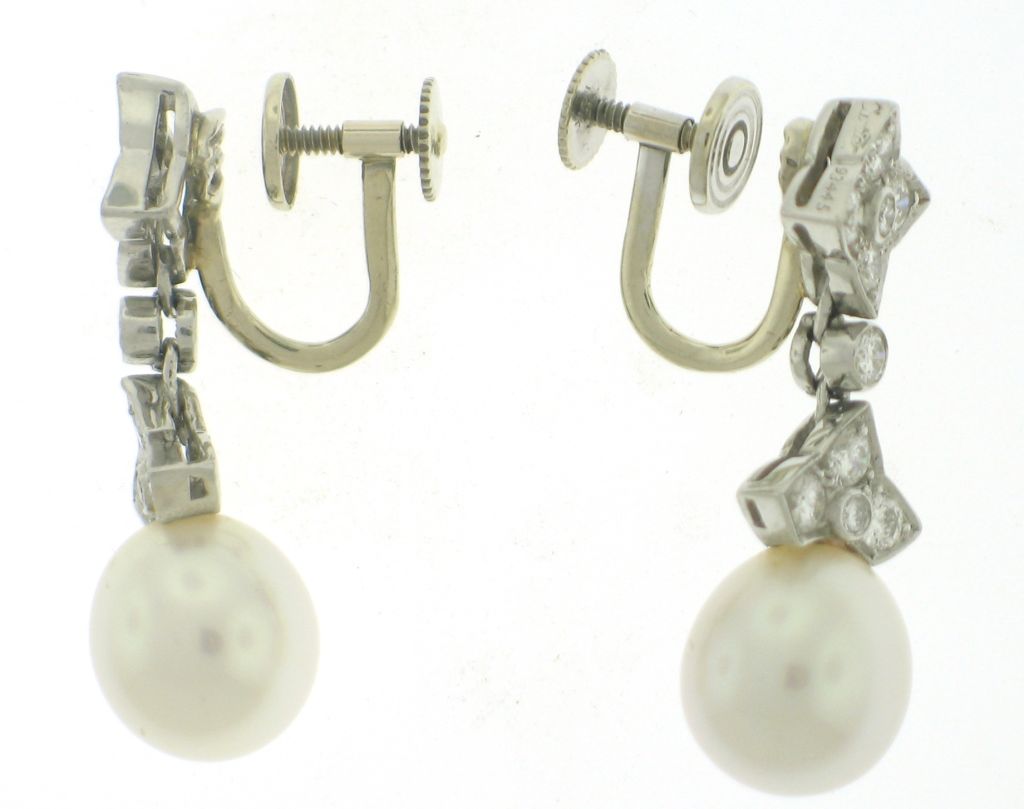 Platinum Cartier earrings with egg shaped pearl drops measuring 12x10.5 millimeters and 20 round diamonds weighing 1.20 carats. 14k white gold earring backs later added. 12.8 grams total weight.