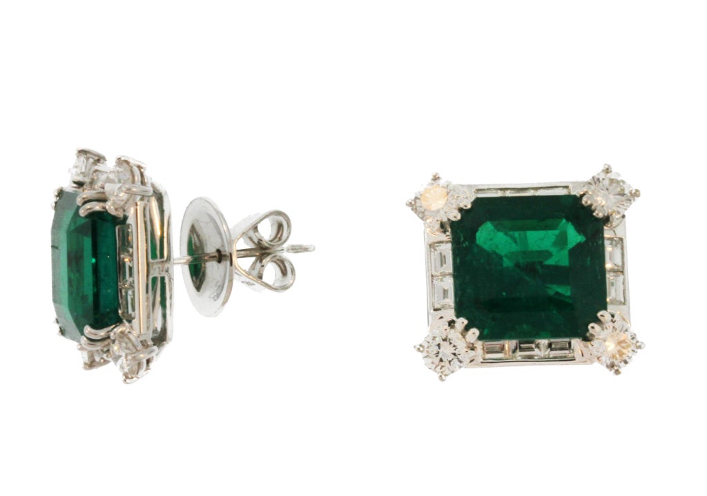 These impressive earrings feature richly colored vivid green and bright Columbian emeralds weighing a total of 12.07 carats, further enhanced by round and baguette diamond frames.  A stunning pair of earrings set with exceptional stones. The