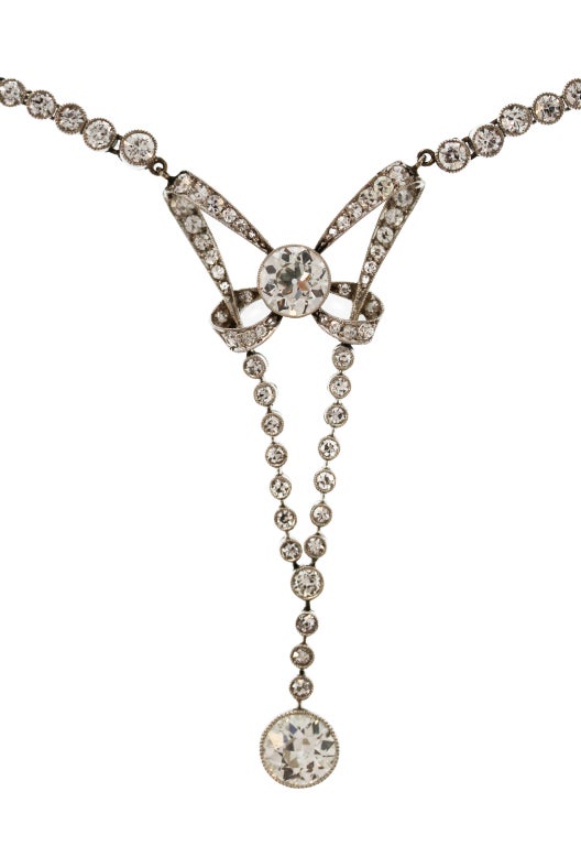 This beautiful necklace centers upon an articulated pendant of ribbon design set with 2 larger old European-cut diamonds weighing a total of approximately 2.40 carats accented by a further 2.75 carats of smaller old round cut diamonds.  A feminine