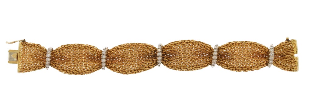 This beautiful bracelet is designed as a wide gold link ribbon gathered by band of diamonds made by the great American firm Oscar Heyman & Brothers. Together with its matching necklace, this bracelet evokes the glamorous era of the 1960s.