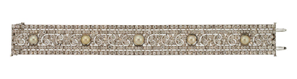 This stunning bracelet is of geometric and openwork design set with 5 pearls of warm honey hue set within a ground of old European-cut diamonds weighing approximately 20.00 carats.  An early piece that can be worn with stacks of bracelets or on its