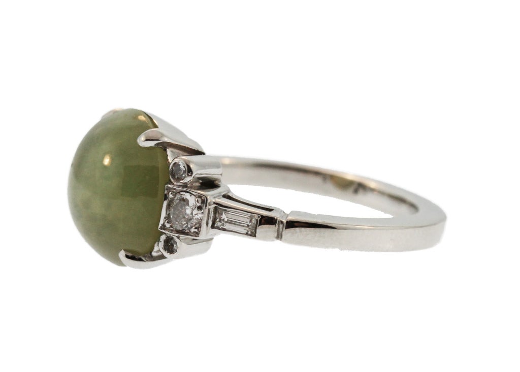 This elegant vintage ring features a round cabochon cat's eye chrysoberyl with an excellent display of chatoyancy (the amazing straight and centralized eye).  Within a platinum setting flanked by diamonds, this ring is a great addition for any gem