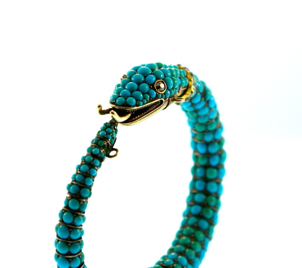 This stunning bracelet is designed as a coiled snake of articulated and tapered design.  Composed of scale-like links set with 294 turquoise cabochon, and the eyes and collar set with 15 old mine diamonds weighing approximately 0.75 carat, length 7