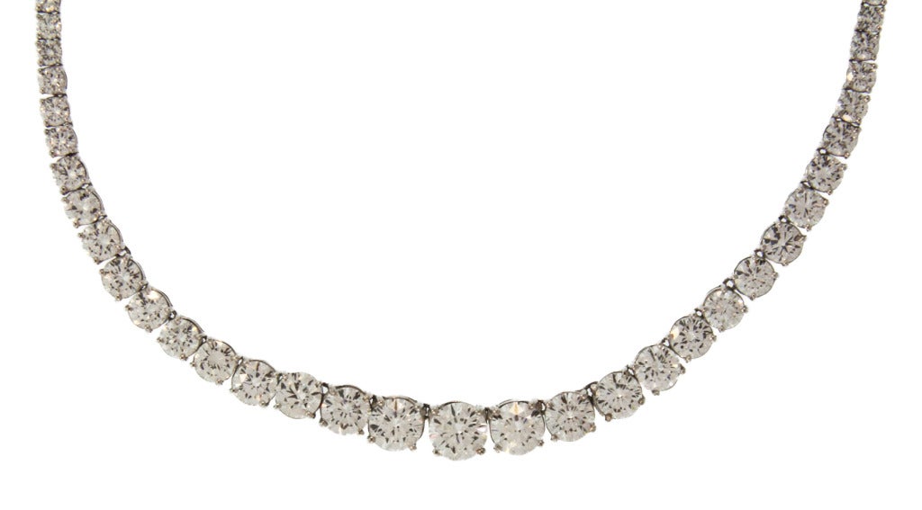 This impressive platinum necklace is of graduated straightline design set with 115 round diamonds weighing approximately 27.00 carats. The 5 center diamonds graduate in size and total 6.05 carats of this total weight, with the largest weighing 1.55
