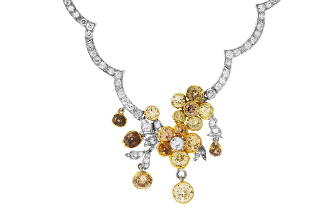 This unique platinum and gold necklace is designed with a floral garland in the center set with 17 old mine diamonds of natural color ranging from yellow to brown weighing approximately 7.25 carats, completed by a scallop link necklace set with 166
