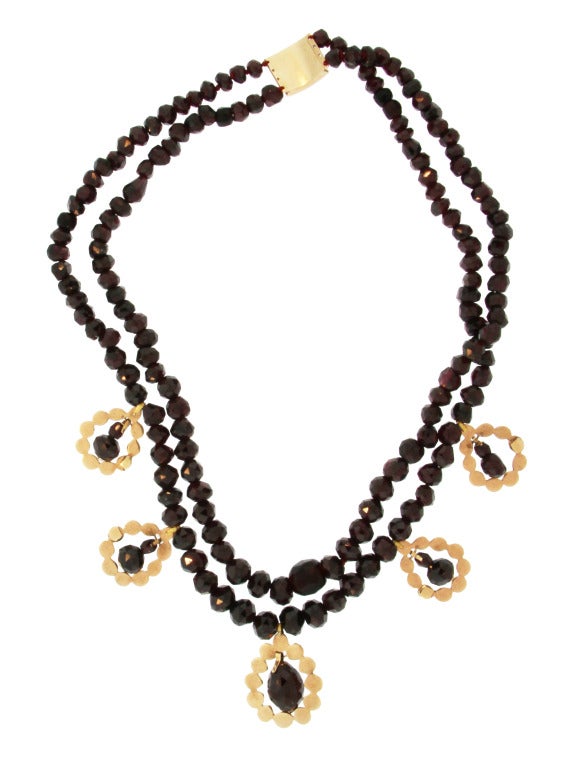 Almost 200 years old and of graduated design composed of two strands of faceted garnet beads supporting five tear-drop pendants set with rose-cut garnets and supporting in the center faceted garnet pendants, mounted in yellow gold, the clasp is