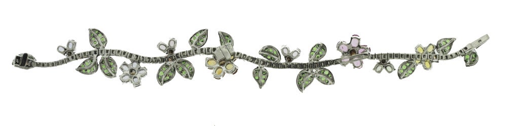 Designed as a meandering vine set with 63 round diamonds weighing approximately 2.50 carats, decorated with flowerheads and leaves, the leaves set with 109 round tsavorite garnets weighing approximately 3.25 carats, the flowerheads set with 7 oval