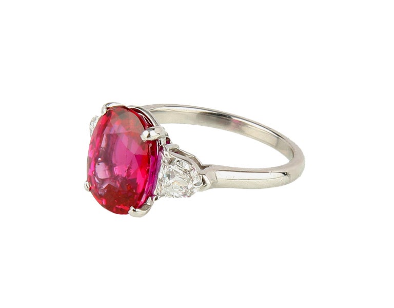 This magnificent ring is set in the center with an oval ruby weighing 4.66 carats, flanked by 2 bullet-shaped diamonds weighing approximately 0.80 carat, mounted in platinum, gross weight 5.2 grams, measuring 1 by 3/4 by 1/2 inches, size 5 3/4,