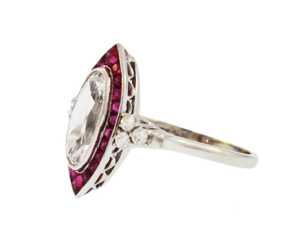 This beautiful diamond and ruby ring is set in the center with an elongated oval old-cut diamond weighing approximately 2.10 carats, approximately H to I color and SI1 clarity, framed by 22 calibre-cut rubies weighing approximately 1.25 carats,