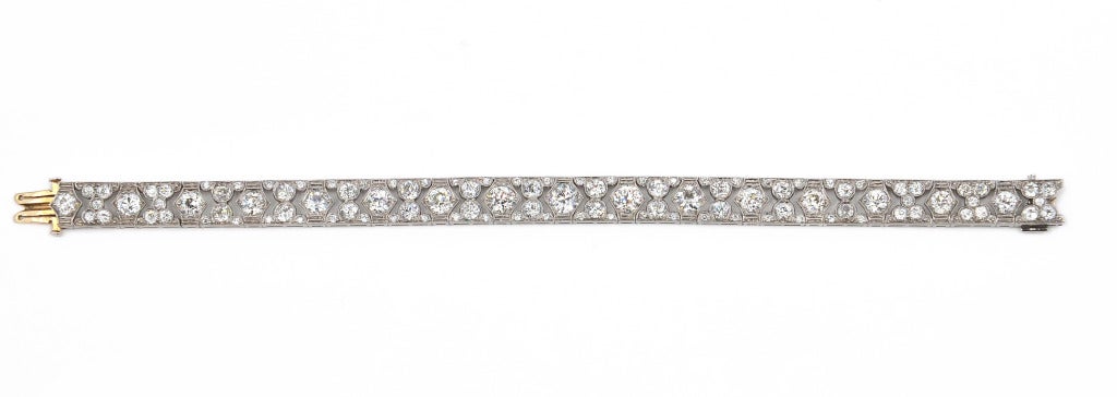 Platinum and Diamond Bracelet, the slightly graduated flexible band of openwork geometric design set with 16 larger old European-cut diamonds weighing approximately 6.40 carats, further set with numerous old European-cut diamonds weighing