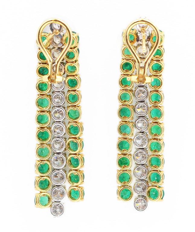 18 karat white and yellow gold, diamond and emerald earclips, of fringe design with three articulated pendants per earclips, set throughout with round diamonds weighing approximately 5.50 carats, and round emeralds weighing approximately 10.00