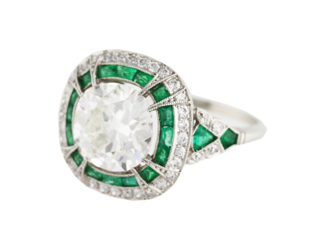 Art Deco platinum, diamond and emerald ring, set in the center with antique cushion-shaped diamond weighing approximately 3.50 carats, framed by small old European cut diamonds weighing approximately 0.40 carat, and calibre-cut emeralds, gross