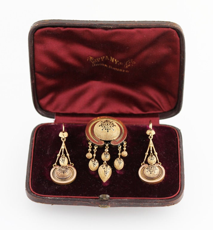 Truly unique, this antique yellow gold and enamel suite was retailed by Tiffany & Co. in the late 19th century.  The suite includes a brooch pendant-earrings with textured domed plaques applied with black enamel pattern, gross weight 19.2 grams,
