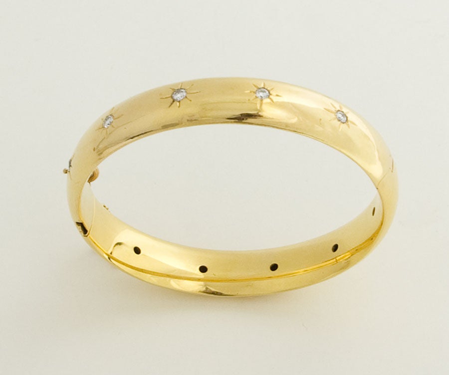 Fourteen karat gold hinged bangle bracelet with 10 diamonds throughout the circumference. Measures 1/2