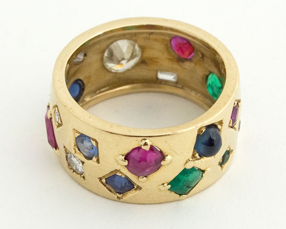 Custom made eighteen karat gold band encrusted with irregularly sized and shaped precious stones. Largest is an oval diamond of about .5 carat which can be worn as the center but not necessarily. It is equally interesting from any point of view.